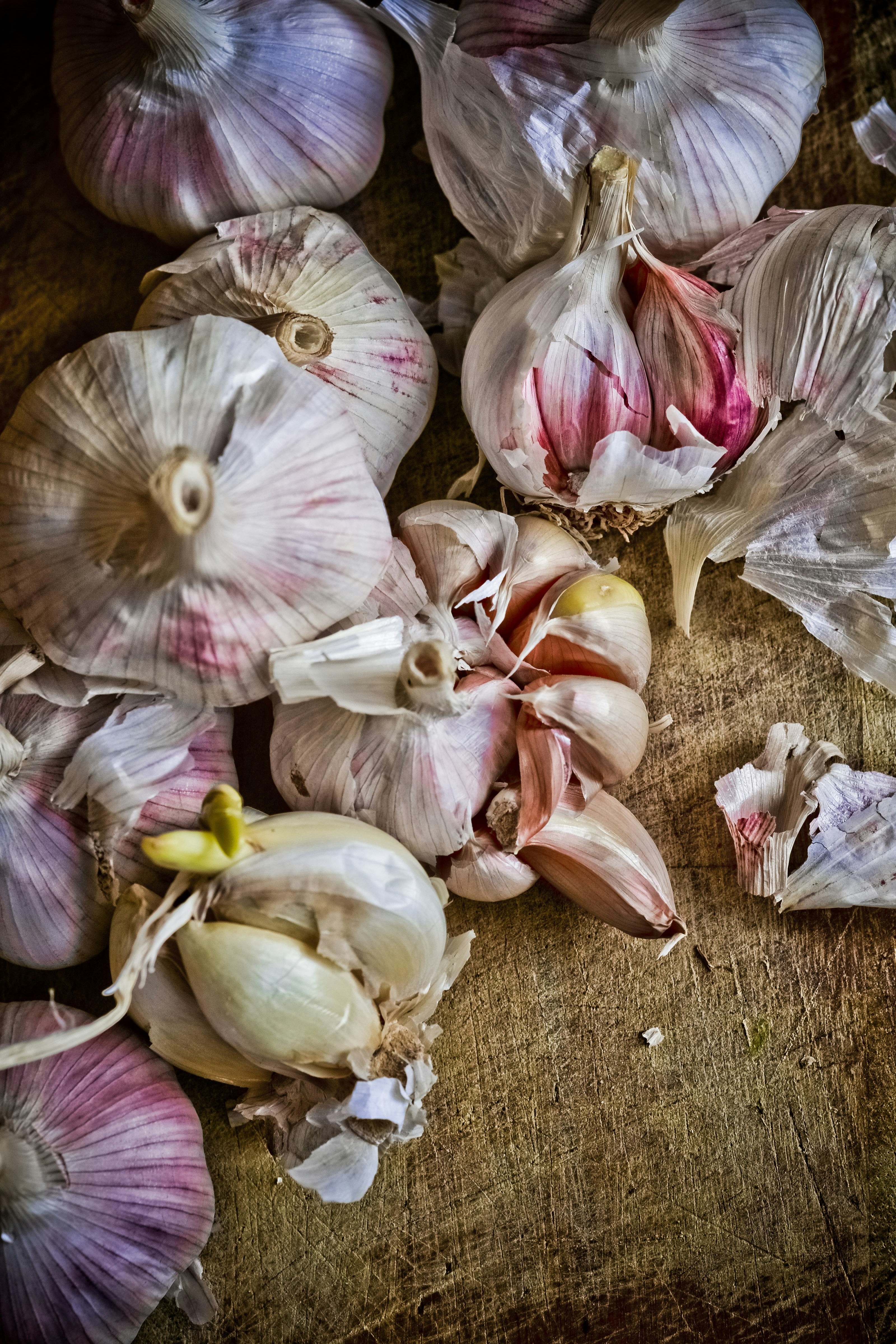 Garlic bulbs and cloves scattered on a rustic wood surface — best garlic varieties for first-time growers